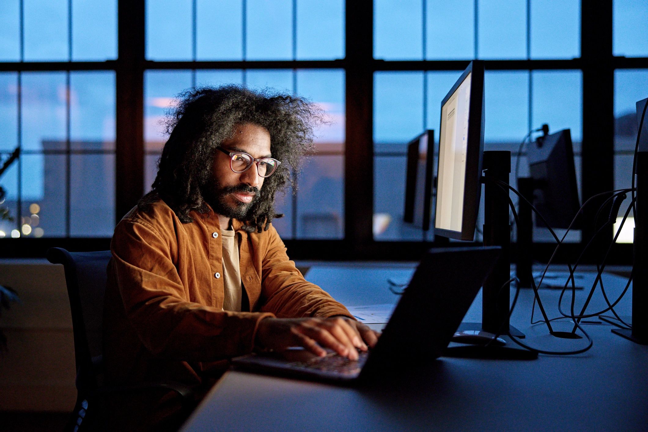 Person working on a laptop at a desk in low light